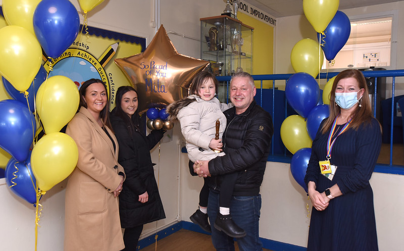 Mila Sneddon and her mum, Lynda, dad, Scott, and older sister, Jodi, alongside Stenhousemuir Primary School headteacher, Dawn Stanfield surrounded by yellow and blue balloons, the school colours
