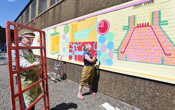 Rowena finalises a section of the mural while Duncan holds an old iron telephone box door that will be turned into an information board, which will be situated by the mural