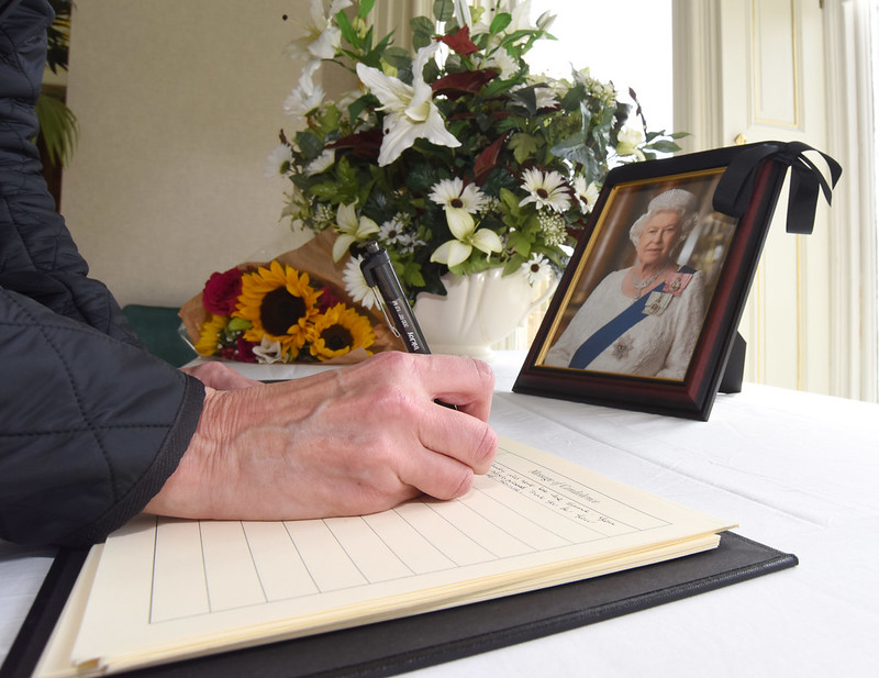 A close up of someone writing in the book of condolence in Callendar House