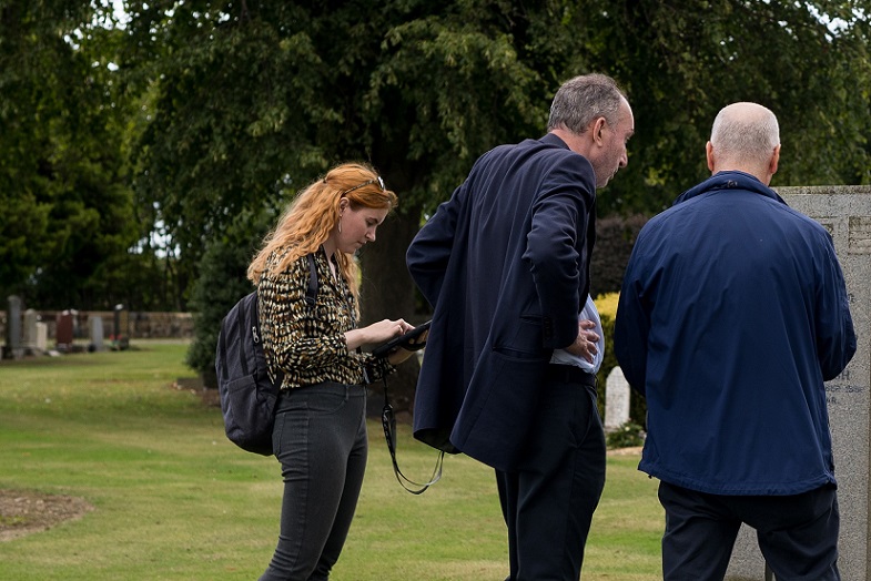 Graduate Natalie Bushell with her tablet helping a couple locate a grave